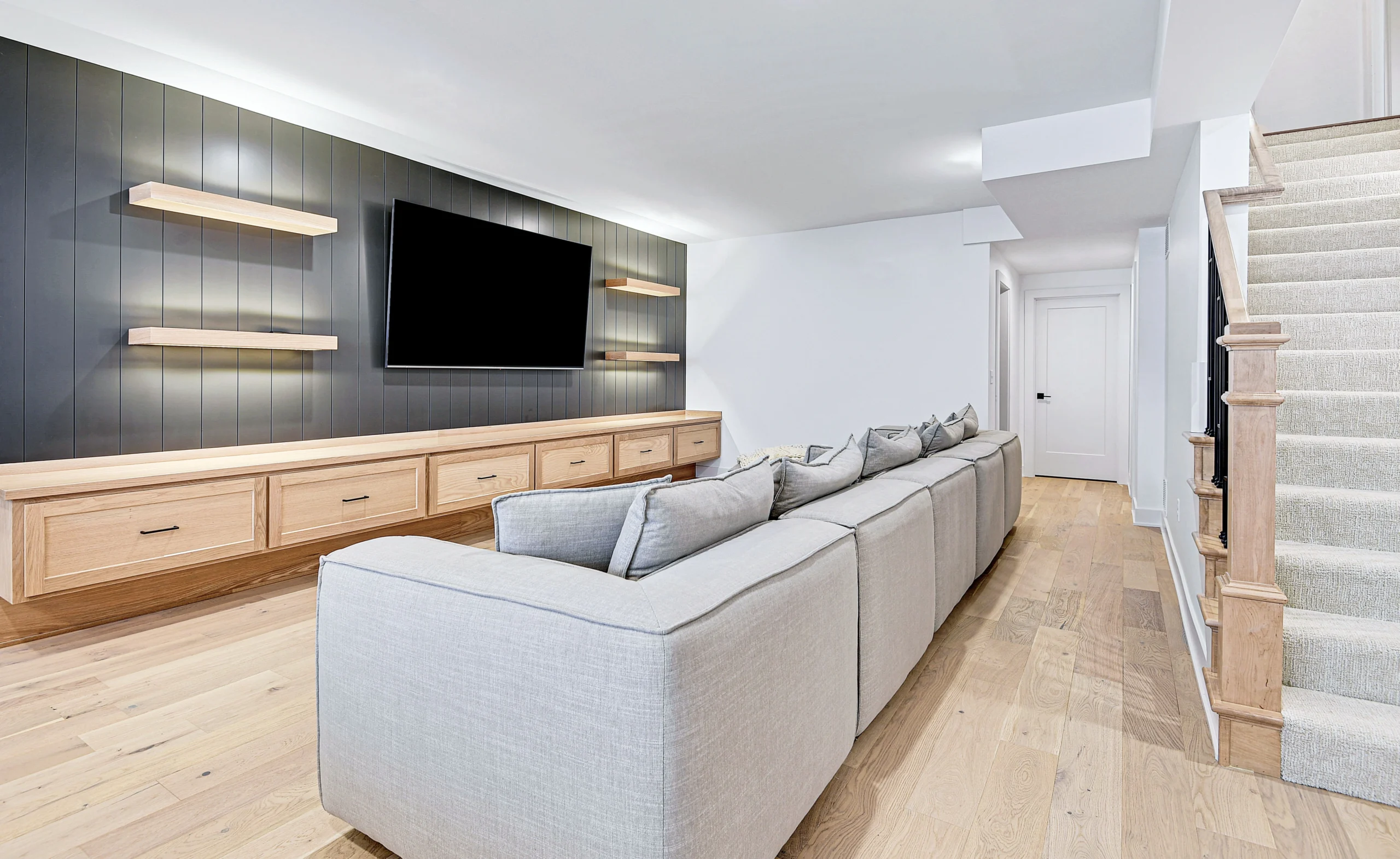 Finished basement seating area with white oak built-ins