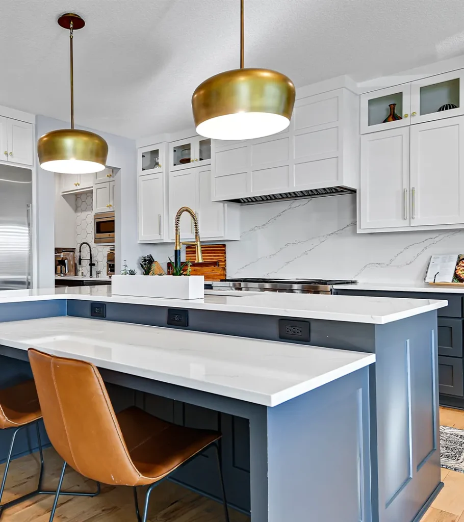 Modern kitchen island with blue cabinetry, white countertops, and brass pendant lights