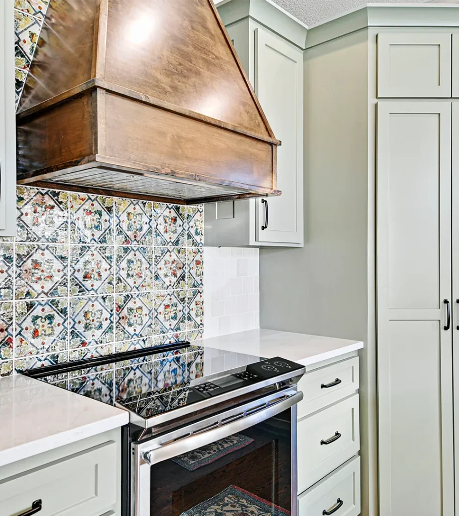 Custom kitchen stove area with copper range hood and patterned tile backsplash