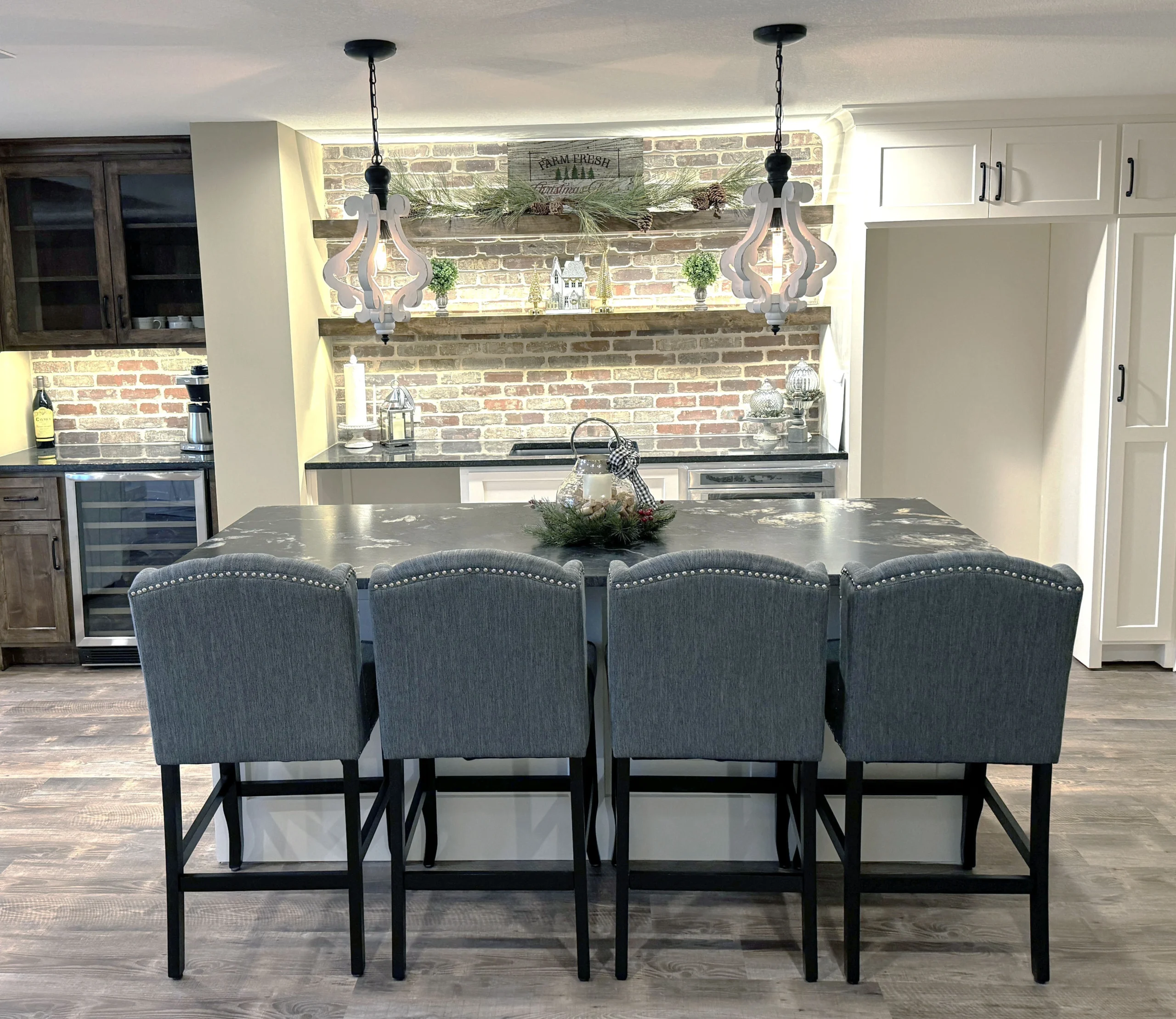 Finished kitchen remodeling project with oversized island seating, brick accent wall, and custom lighting