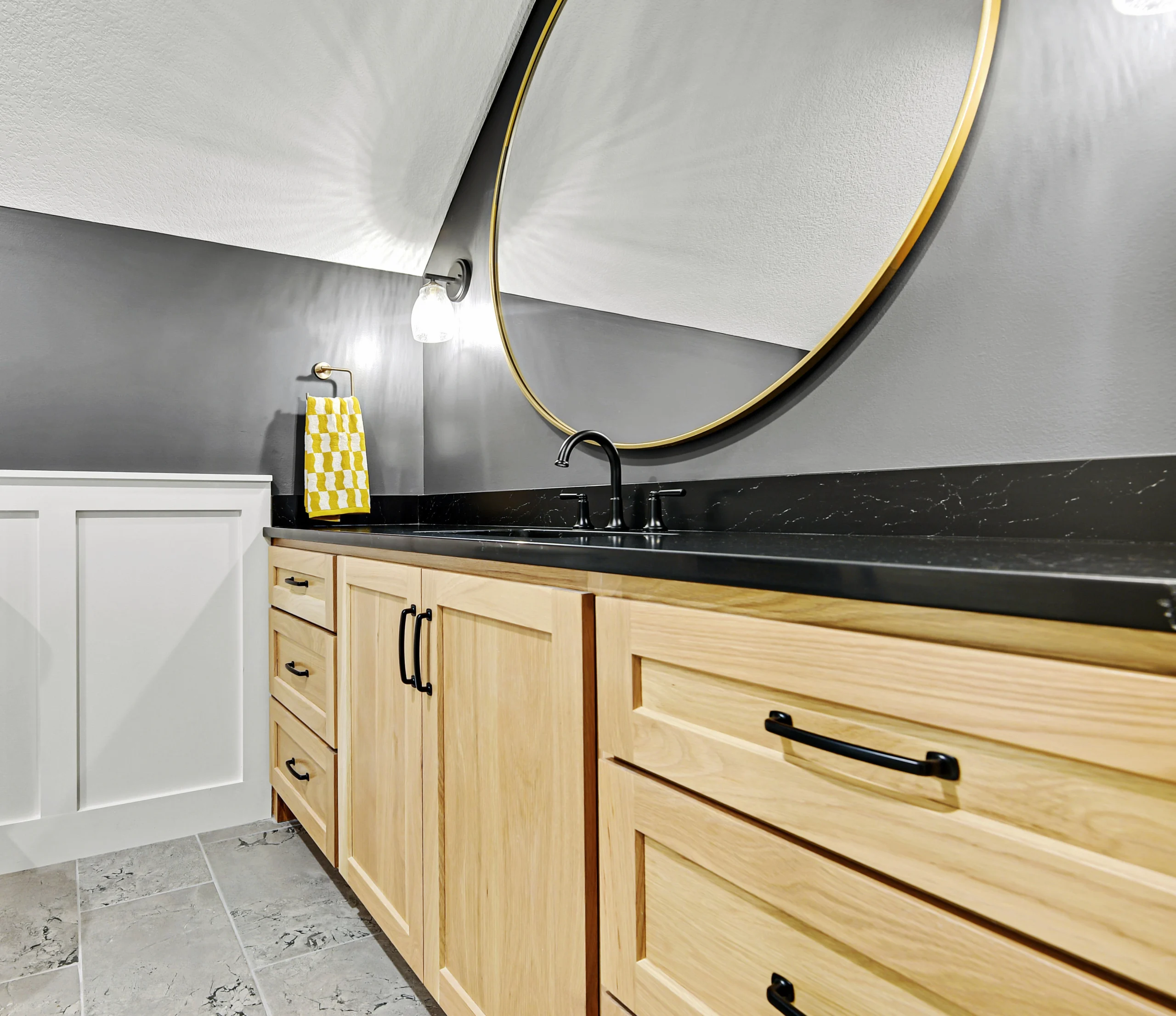 Modern bathroom remodel featuring natural wood vanity cabinets and black countertop
